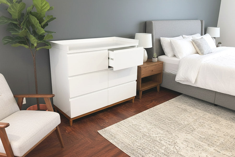 Cambiador grande con cajones abiertos en dormitorio, mueble funcional para organizar pañales y ropa de bebé.